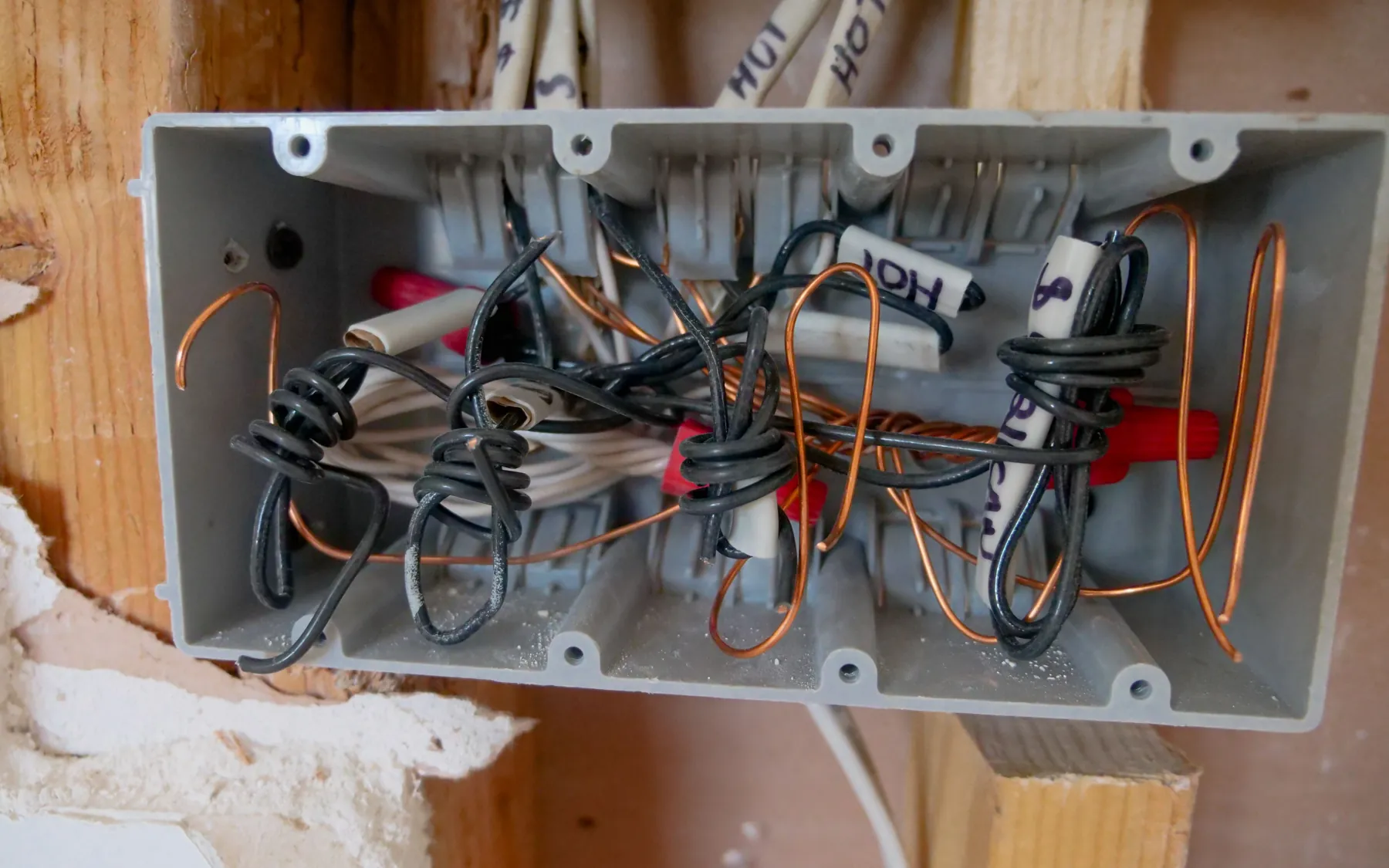 Wires pulled into an open junction box in a stud wall during a rewire